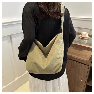 Detailed view of spacious ruched nylon hobo bag in light green worn by model indoors