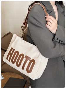 Détail du cabas en toile avec écusson HOOTO marron et bandoulière chaîne dorée