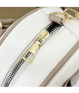Detailed close-up of smooth gold-tone metal zipper and beige contrast leather texture
