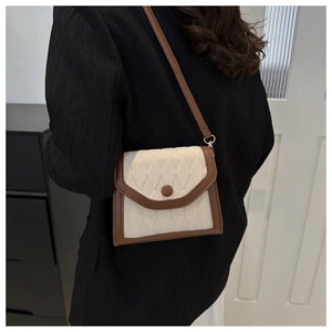 Détail du petit sac à bandoulière matelassé beige avec bordures en cuir marron