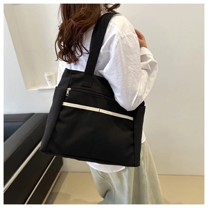 Vista posteriore della borsa tote in tela nera con striscia bianca e tasca con zip
