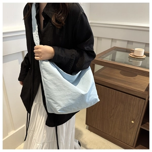 Close-up of light blue hobo bag with pleated nylon texture on a casual outfit