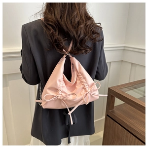 Detailed view of pink bow backpack with pleated nylon fabric and silver chain strap