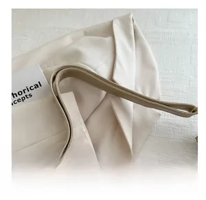 Detail of beige faux leather shoulder strap with neat double stitching on a matching blazer