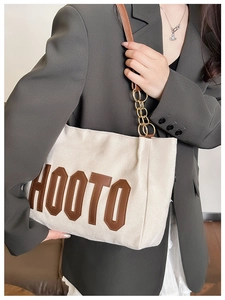 Détail du sac cabas en daim beige avec patch HOOTO en cuir et bandoulière dorée
