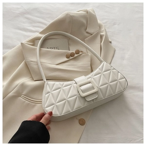 Détail du sac à bandoulière matelassé blanc avec coutures triangulaires sur fond beige