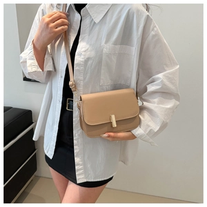Detail of minimalist golden metal lock and matte beige synthetic leather on small square bag