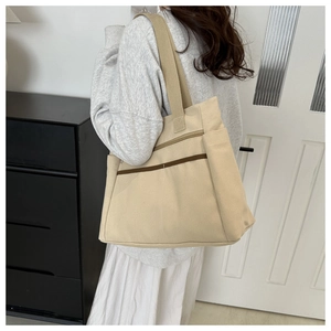 Dettaglio della borsa tote in tela bianco sporco con tasche laterali e fascia marrone