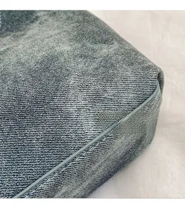 Detailaufnahme von grauem Denim-Stoff mit verstärkter Paspelung an der Umhängetasche