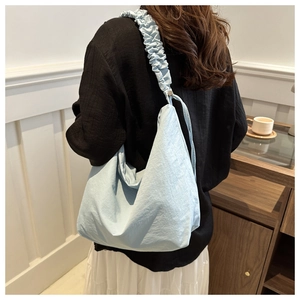 Close-up of light blue canvas tote bag featuring wide gathered pleated shoulder strap detail