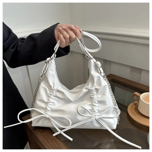 Detail view of white ruched backpack with bow accents and silver chain handles