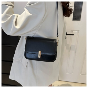 Detail of minimalist black crossbody bag with golden cylindrical metal lock on the side