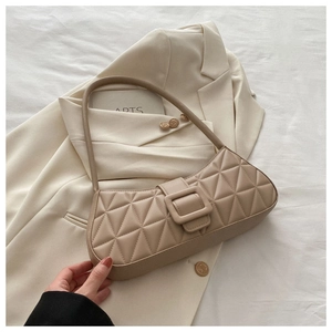 Gros plan détaillé du sac baguette matelassé beige avec boucle sur un blazer blanc