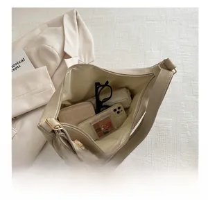 Top view of large beige hobo bag showing spacious interior with daily essentials and bear charm