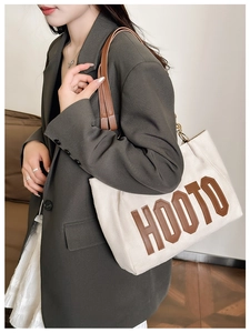 Détail du cabas en toile crème avec écusson HOOTO en cuir marron et anses en cuir