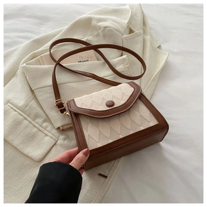 Détail de la texture à losanges et du fermoir bouton vintage sur ce petit sac bandoulière