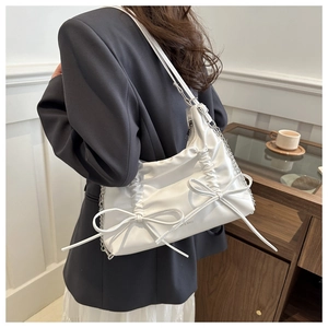 Detail of white pleated shoulder bag with large bow decorations and silver chain