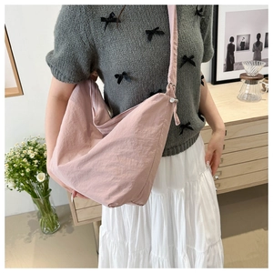 Detail of light pink crescent nylon crossbody bag with textured fabric and wide strap