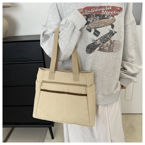 Dettaglio della grande borsa tote in tela beige con tasche funzionali e ampi manici