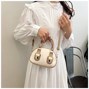 Detail of elegant two-tone Boston bag with golden lock and leather shoulder strap