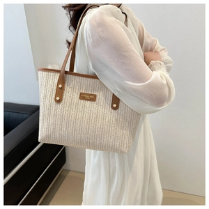 Detail of cream woven tote bag with brown leather straps and metal rivet accents