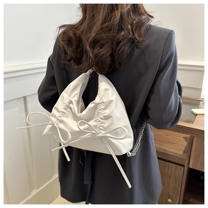 Detail of white matte backpack with bow drawstring and silver chain strap on model