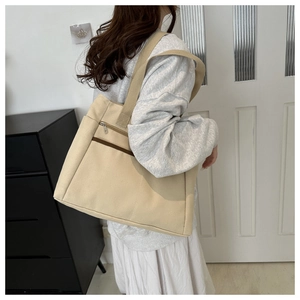 Detail of beige canvas tote bag with front zipper pocket and reinforced shoulder strap