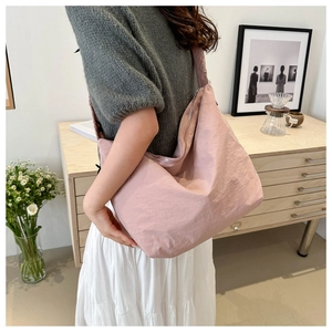 Macro detail of pink nylon hobo bag featuring smooth silver zipper and textured fabric