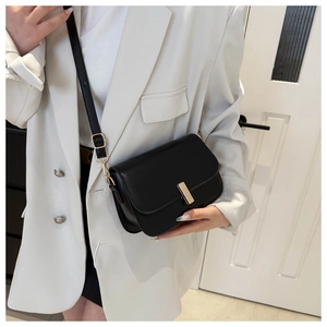 Detailed view of black matte leather crossbody bag with elegant gold buckle on model