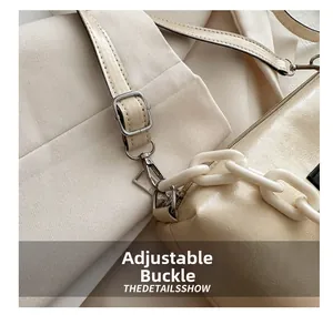 Detail of adjustable silver buckle and acrylic chain on the beige shoulder bag