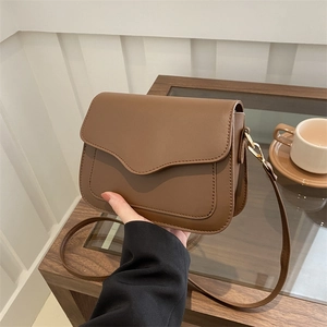 Minimalist brown faux leather crossbody bag with stylish wavy flap and adjustable strap