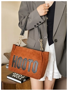 Gros plan du sac cabas en daim marron avec un écusson à lettres noires HOOTO brodé