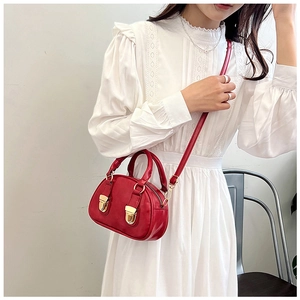 Detail of red oil-wax leather mini Boston bag with gold buckles on model