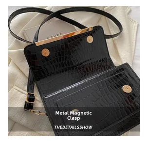 Close-up of black crocodile pattern leather bag with golden magnetic snap closure details