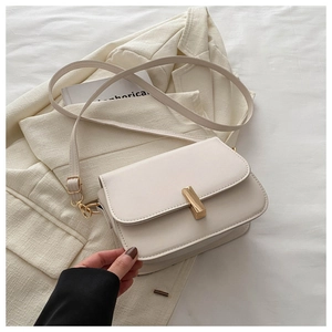 Close-up of cream crossbody bag with gold metal buckle on a beige blazer background