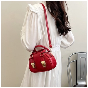 Detail of vintage red crossbody pillow bag with gold metal buckles and top handle strap