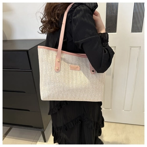 Macro view of woven tote with pink leather handle and gold rivet details on the shoulder strap