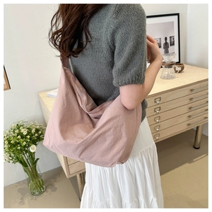 Detail of light pink oversized tote bag featuring a textured pleated shoulder strap