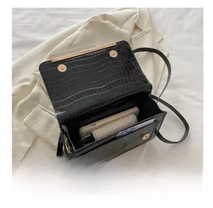 Detail view of the interior compartment and crocodile texture of the black crossbody bag