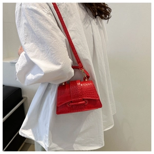 Detailed shot of a red crocodile pattern mini crossbody bag worn with a white shirt