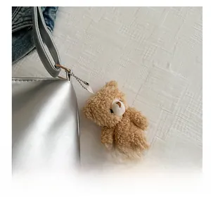 Close-up of a brown fluffy teddy bear charm with silver bead chain on a handbag