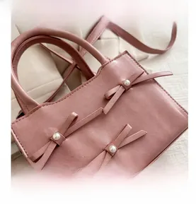 Dettaglio della borsa rosa in finta pelle con fiocchi e decorazioni di perle