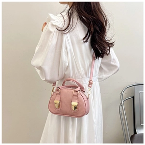 Detailed view of pink Boston bag featuring gold hardware and a model in a white dress