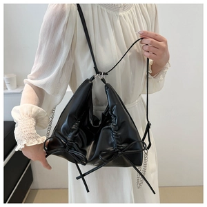 Detailed view of black bow-knot tote bag with faux leather pleats and silver chain strap