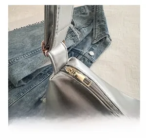 Detailed macro shot of a smooth gold metal zipper on a silver metallic tote bag