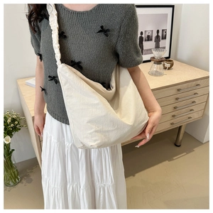 Detail of minimalist cream crossbody bag featuring unique pleated shoulder strap design