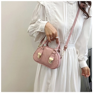Detail view of a pink pillow handbag featuring gold metal buckles and a crossbody strap