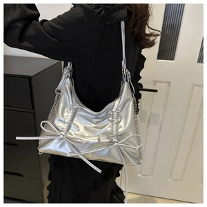 Silver metallic pleated shoulder bag with bow accents and chain strap on model