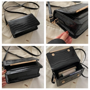 Detail of black crocodile texture crossbody bag with gold metal trim and magnetic flap closure