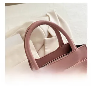 Dettaglio borsa a mano rosa con fiocco decorativo, perle e chiusura a zip sicura